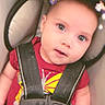 baby, child, car_seat, seatbelt, straps, red_shirt, plaid_pants, flower_filter, face, eyes, infant, cute, sitting, indoors, portrait, child_safety, expression, head, person, young