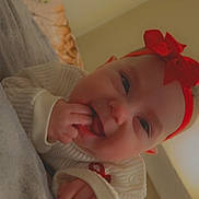 Jesira joined the competition — help win amazing prizes! baby, infant, smiling, red_bow, headband, white_sweater, hand, bed, blanket, finger_in_mouth, cute, happy, indoors, portrait, child, playful, warm_lighting, heart_emoji, cozy, lying_down