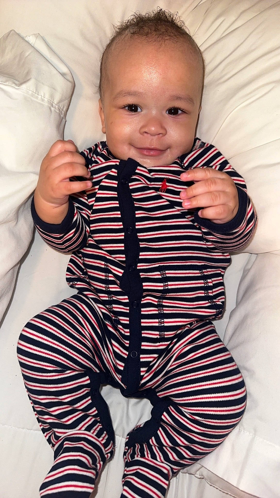 Kaiser is registered to the contest to win money with this photo: arm, baby, baby_toddler_clothing, cheek, collar, eye, face, finger, gesture, happy, head, iris, neck, person, skin, sleeve, smile, standing, textile, thumb