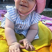Cassandre a rejoint le concours — aidez-le/la à gagner de superbes lots ! baby, child, smile, drool, hat, striped_clothing, outdoor, blanket, grass, sunlight, happy, cute, infant, hand, face, person, toddler, summer, playtime, closeup