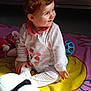toddler, child, smiling, plush_toy, panda, ball, blanket, colorful, white_outfit, fruit_pattern, indoor, sunlight, happy, sitting, curly_hair, cute, playtime, soft_toys, portrait, baby