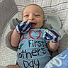 baby, infant, smiling, onesie, mittens, cushion, patterned, indoor, happy, person, face, clothing, head, baby_gesture, baby_accessory, cute, newborn, baby_boy, portrait, celebration