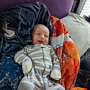Jaxon joined the competition — help win amazing prizes! baby, smiling, blanket, pillow, bed, onesie, striped_clothing, infant, happy, cozy, sleepwear, child, indoor, soft_lighting, cute, person, portrait, resting, comfortable, young