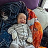baby, smiling, blanket, pillow, bed, onesie, striped_clothing, infant, happy, cozy, sleepwear, child, indoor, soft_lighting, cute, person, portrait, resting, comfortable, young