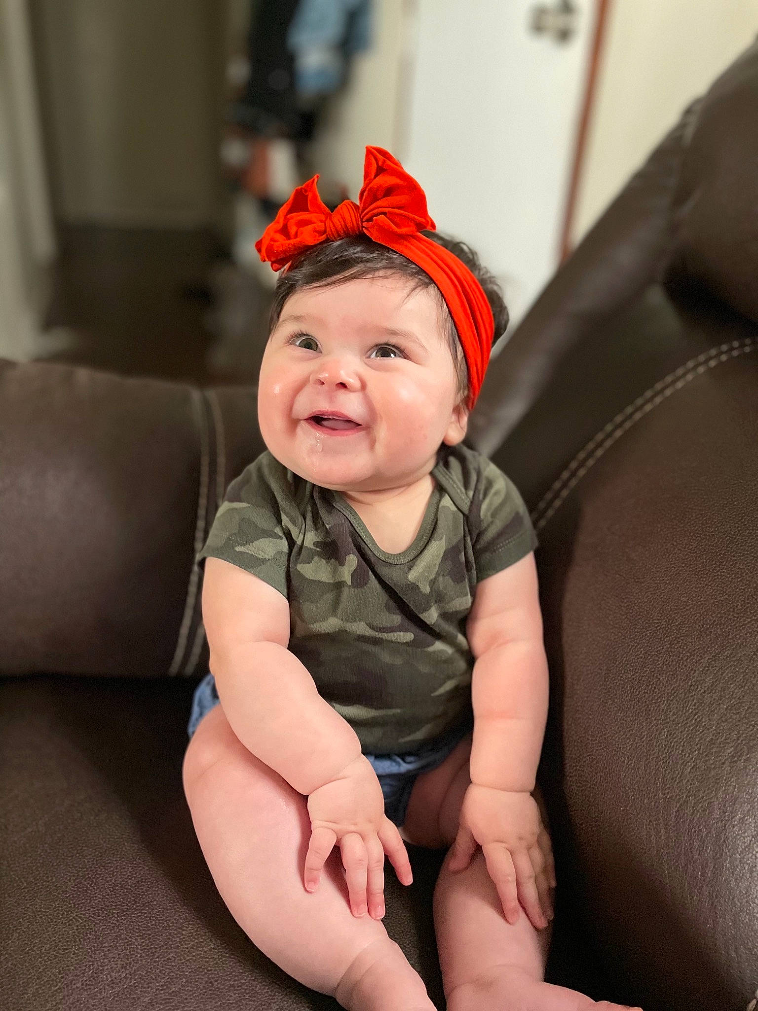 Vada is registered to the contest to win money with this photo: baby, baby_toddler_clothing, cap, carmine, chin, comfort, costume_hat, couch, eye, fashion_accessory, flash_photography, foot, fun, happy, headpiece, headwear, human_leg, joy, lip, person