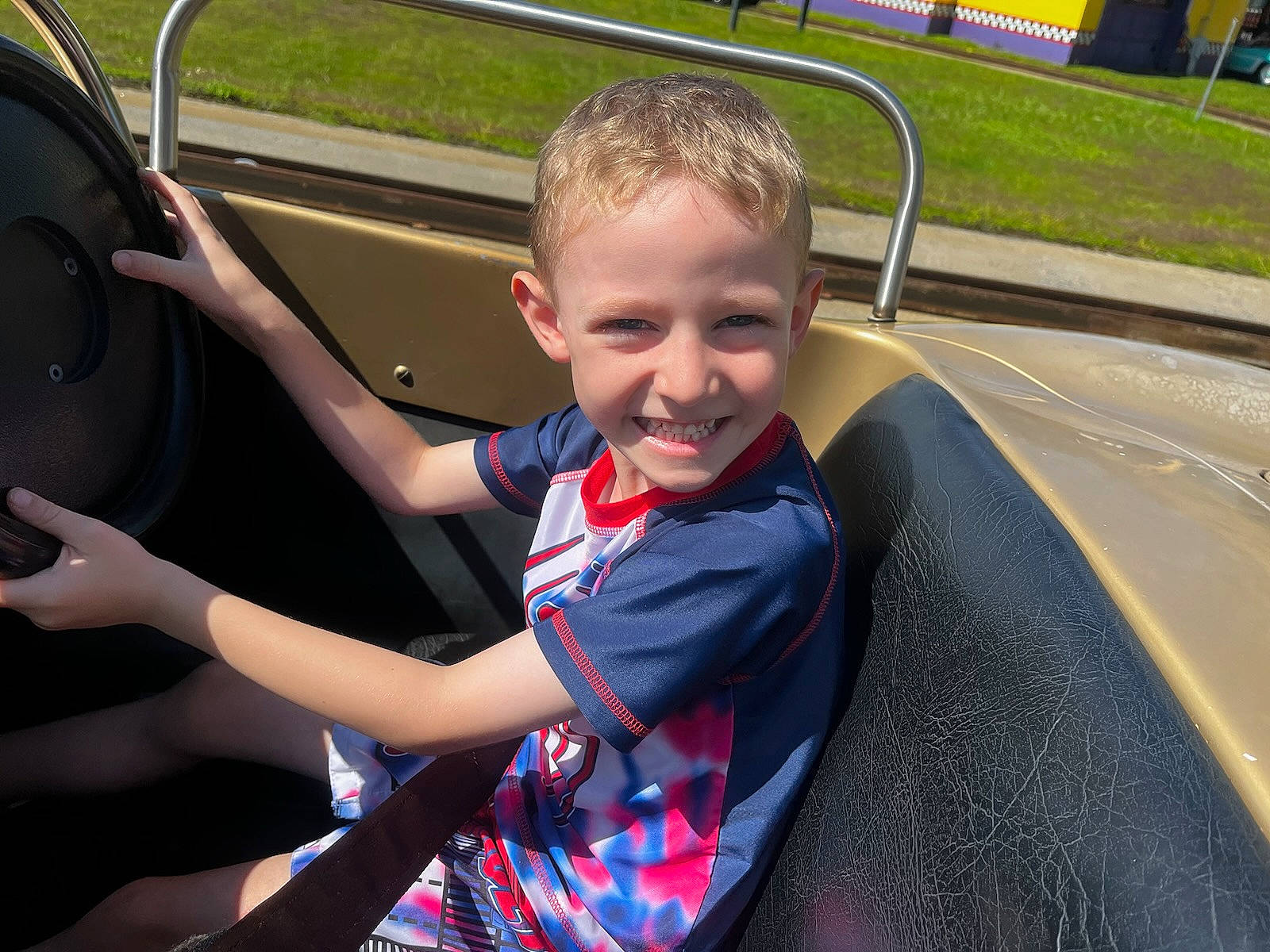 Andy is registered to the contest to win money with this photo: auto_part, automotive_design, automotive_exterior, automotive_tire, bumper, car, child, door, fun, joy, leisure, motor_vehicle, person, plant, recreation, smile, steering_wheel, toddler, tree, vehicle