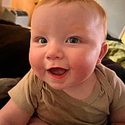 Conrad is registered to the contest to win money with this photo: baby, beige_shirt, blue_eyes, cheerful, child, closeup, cute, expression, face, happy, head, indoors, infant, person, portrait, rosy_cheeks, skin, smiling, soft_light, young