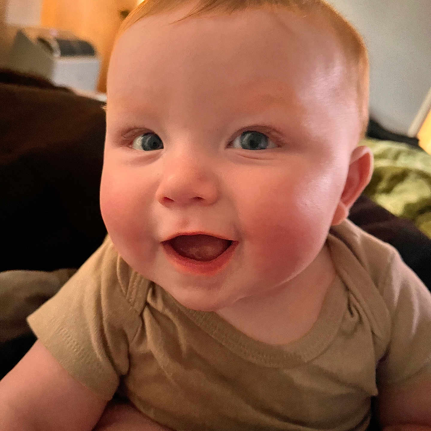 Conrad is registered to the contest to win money with this photo: baby, beige_shirt, blue_eyes, cheerful, child, closeup, cute, expression, face, happy, head, indoors, infant, person, portrait, rosy_cheeks, skin, smiling, soft_light, young