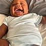 baby, child, infant, laughing, onesie, smiling, happy, lying_down, bed, pillow, skin, face, mouth_open, joyful, cute, indoor, human, person, clothing, sleepwear