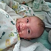 Leo joined the competition — help win amazing prizes! baby, blanket, smile, face, infant, newborn, child, soft, cozy, patterned_blanket, sleeping_area, cute, wrapped, indoors, closeup, head, expression, comfort, resting, person