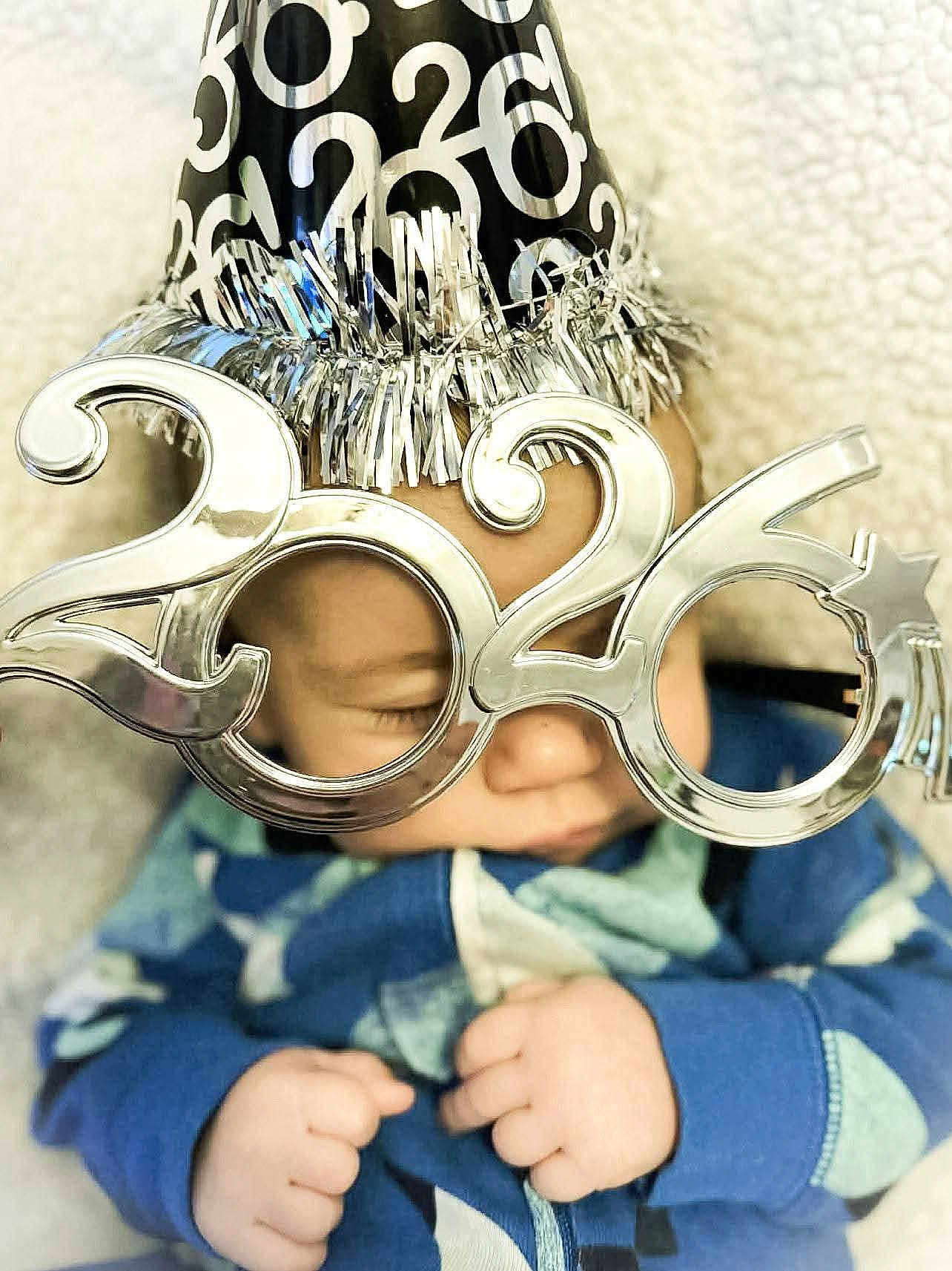 Leo joined the competition — help win amazing prizes! baby, sleeping, party_hat, glasses, 2026, celebration, new_year, infant, cute, hands, face, blue_clothing, closeup, festive, soft_texture, portrait, indoors, peaceful, child, holiday