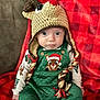 Leo is registered to the contest to win money with this photo: baby, child, infant, hat, crochet, reindeer, christmas, holiday, green_overalls, plaid_blanket, braided_tassels, cute, festive, sitting, portrait, indoor, cozy, wide_eyes, clothing, soft_toys
