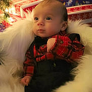 Leo is registered to the contest to win money with this photo: baby, infant, plaid_shirt, black_suspender, fluffy_blanket, christmas_lights, holiday_presents, festive, cozy, indoors, celebration, cute, portrait, child, warm, smiling, decorations, seasonal, holiday, background