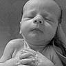 newborn, baby, sleeping, portrait, black_and_white, close_up, face, hands, clasped_hands, indoors, blanket, lying_down, peaceful, infant, head, skin, phone_screenshot, gallery_interface, wall, electrical_outlet