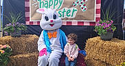 Leah joined the competition — help win amazing prizes! child, easter_bunny, costume, hay_bales, flowers, sign, blue_canopy, grass, outdoor, spring, festive, celebration, pink_flowers, purple_flowers, greenery, smiling, person, cute, holiday, event