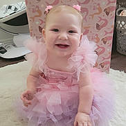 Aliyah joined the competition — help win amazing prizes! baby, child, pink_dress, tutu, hair_accessories, smiling, sitting, carpet, indoor, happy, cute, face, person, playful, soft, decor, floor, baby_girl, toddler, portrait