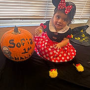 Isa joined the competition — help win amazing prizes! toddler, child, pumpkin, costume, minnie_mouse, polka_dots, red, black, yellow_socks, window, blinds, smile, indoor, table, decoration, halloween, black_cat_design, cute, dress, face