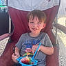 Noah Thompson is registered to the contest to win money with this photo: american_flag, blue_straw, boy, casual_clothing, chair, child, food, fun, grey_shirt, happy, outdoor, plastic_spoon, recreation, relaxation, shaved_ice, smiling, snack, summer, sunlight, umbrella