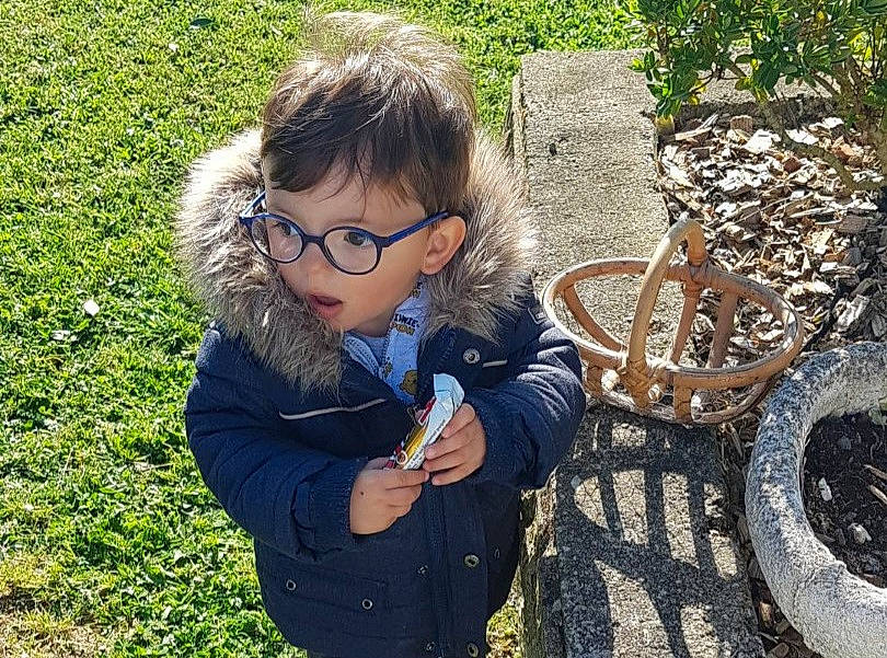 émiliano a rejoint le concours — aidez-le/la à gagner de superbes lots ! automotive_tire, bicycle_tire, botany, eyewear, fun, glasses, grass, happy, jacket, leaf, leisure, people_in_nature, person, plant, sitting, tire, toddler, vertebrate, vision_care, wheel