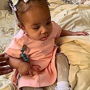 Xalori is registered to the contest to win money with this photo: baby, bed, blanket, bows, child, curious, cute, floral_pattern, girl, hair_accessories, hand, indoors, person, pillow, pink_dress, seated, skin, socks, soft_lighting, toddler