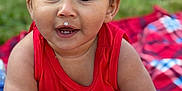 Zaiden is registered to the contest to win money with this photo: baby, child, red_clothing, toy, blanket, outdoor, grass, face, expression, drool, hands, play, colorful, plaid, infant, cute, person, smiling, sitting, curious