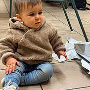 Lyam a rejoint le concours — aidez-le/la à gagner de superbes lots ! child, toddler, indoor, floor, tile, jeans, jacket, fleece, shoes, wrapping_paper, curious, sitting, hands, face, hair, person, casual, expression, flooring, unwrapping