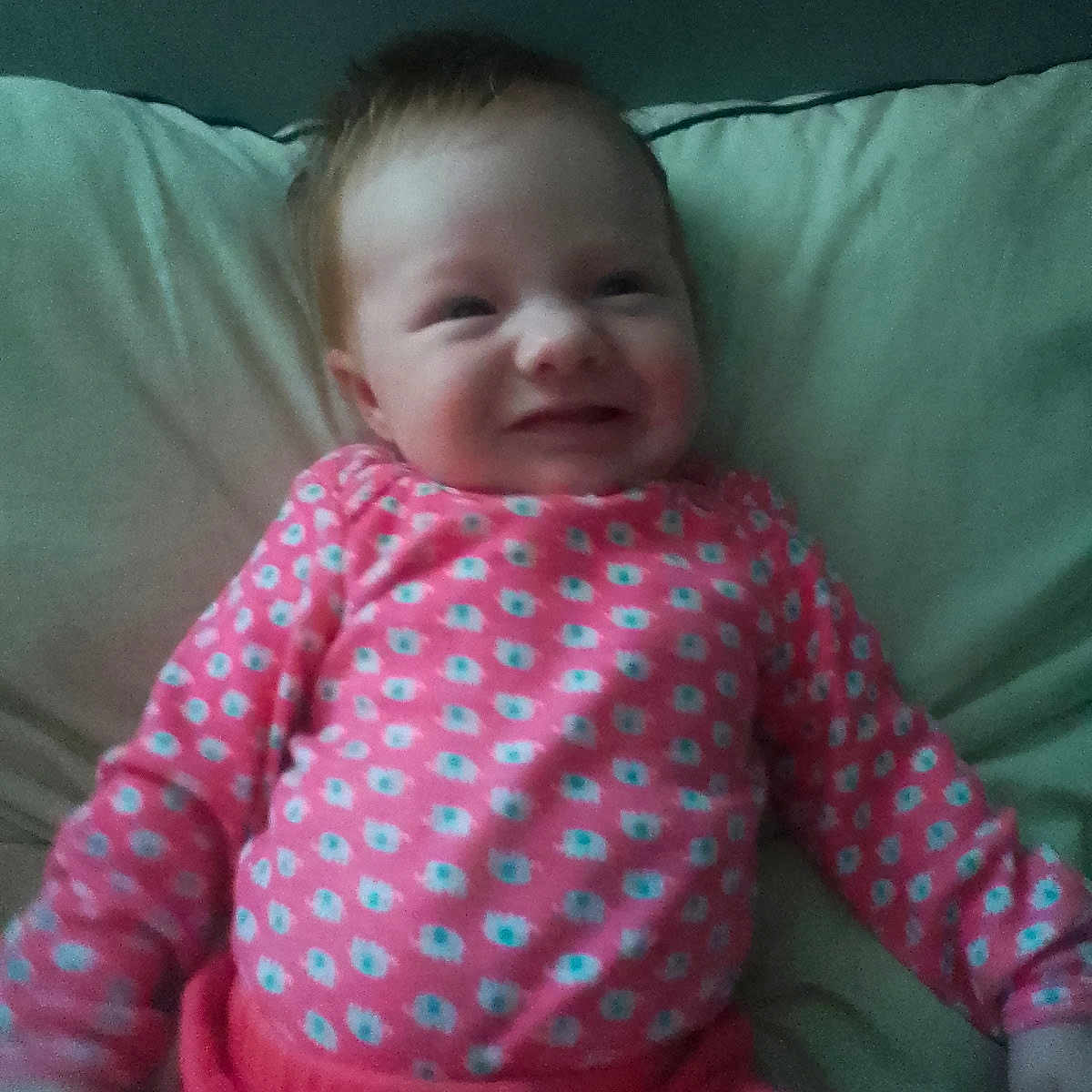 Arissa joined the competition — help win amazing prizes! baby, bow, child, cozy, cute, face, hand, happy, head, indoors, infant, lying_down, patterned_clothing, person, pillow, pink_clothing, sleeve, smile, soft_lighting, young_child