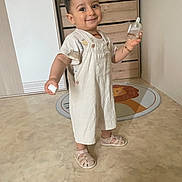 Isaak a rejoint le concours — aidez-le/la à gagner de superbes lots ! bottle, child, clothing, cute, dresser, face, floor, happy, home, indoor, lion_rug, marble_floor, person, rug, sandals, shoes, smiling, standing, toddler, toy