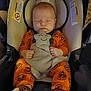 Dakota joined the competition — help win amazing prizes! baby, sleeping, car_seat, orange_clothing, pumpkin_pattern, plush_toy, soft_toy, socks, child, infant, cute, cozy, indoor, resting, peaceful, head_support, blanket, hands, face, comfort