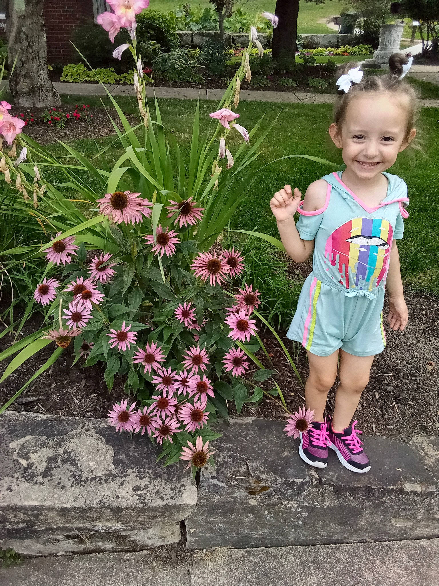 Mia Grace is registered to the contest to win money with this photo: annual_plant, baby_toddler_clothing, botany, flower, flower_arranging, grass, green, groundcover, happy, joy, magenta, people_in_nature, person, petal, pink, plant, shorts, shrub, smile, terrestrial_plant