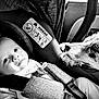 baby, infant, car_seat, dog, paw, black_and_white, car_interior, straps, pacifier, closeup, face, pet, animal, child, transportation, seatbelt, comfort, bond, trust, portrait