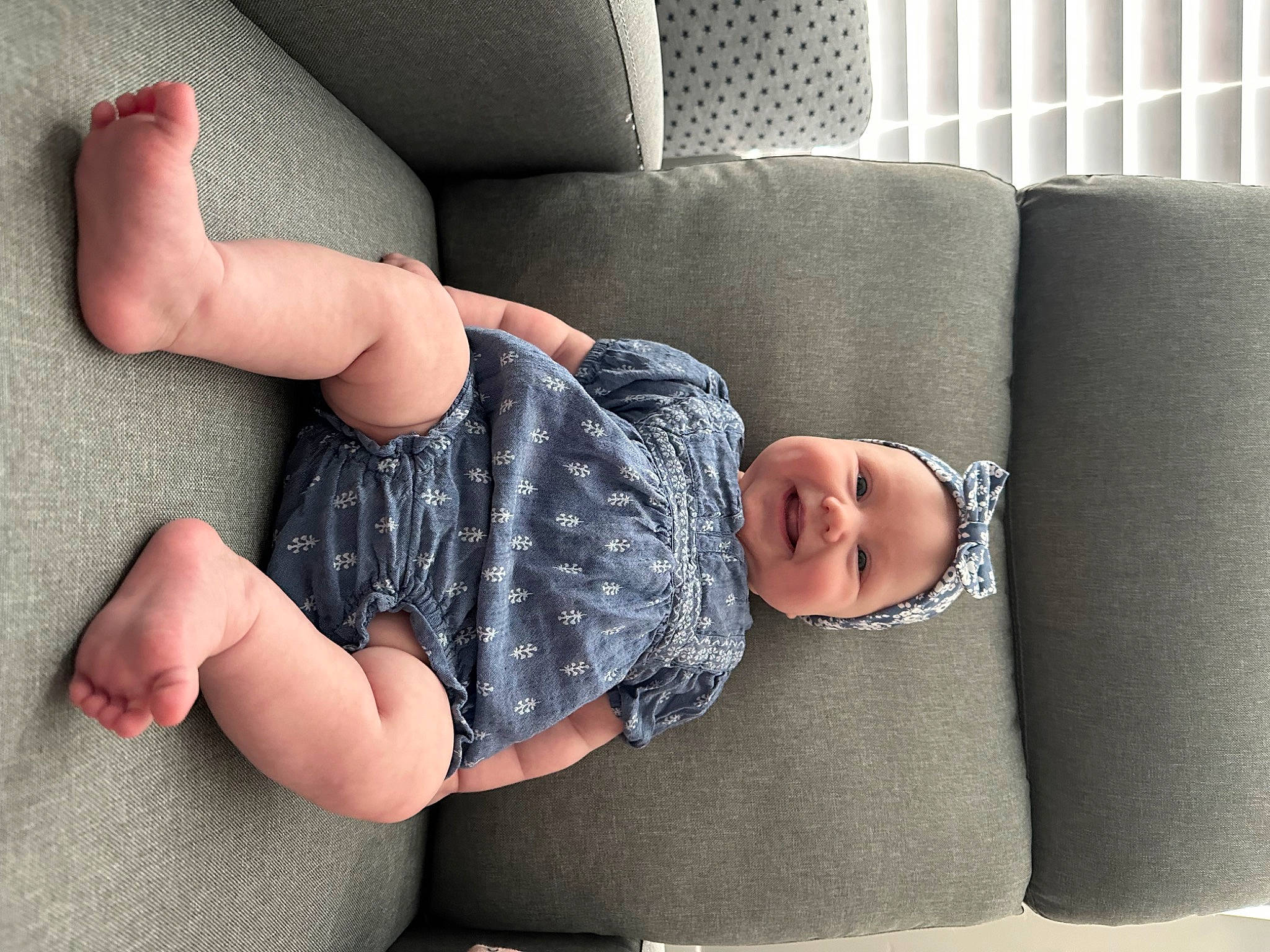 Hannah is registered to the contest to win money with this photo: baby, baby_toddler_clothing, barefoot, comfort, couch, elbow, finger, flooring, foot, grey, hand, headwear, human_body, human_leg, joint, joy, knee, leg, person, sleeve