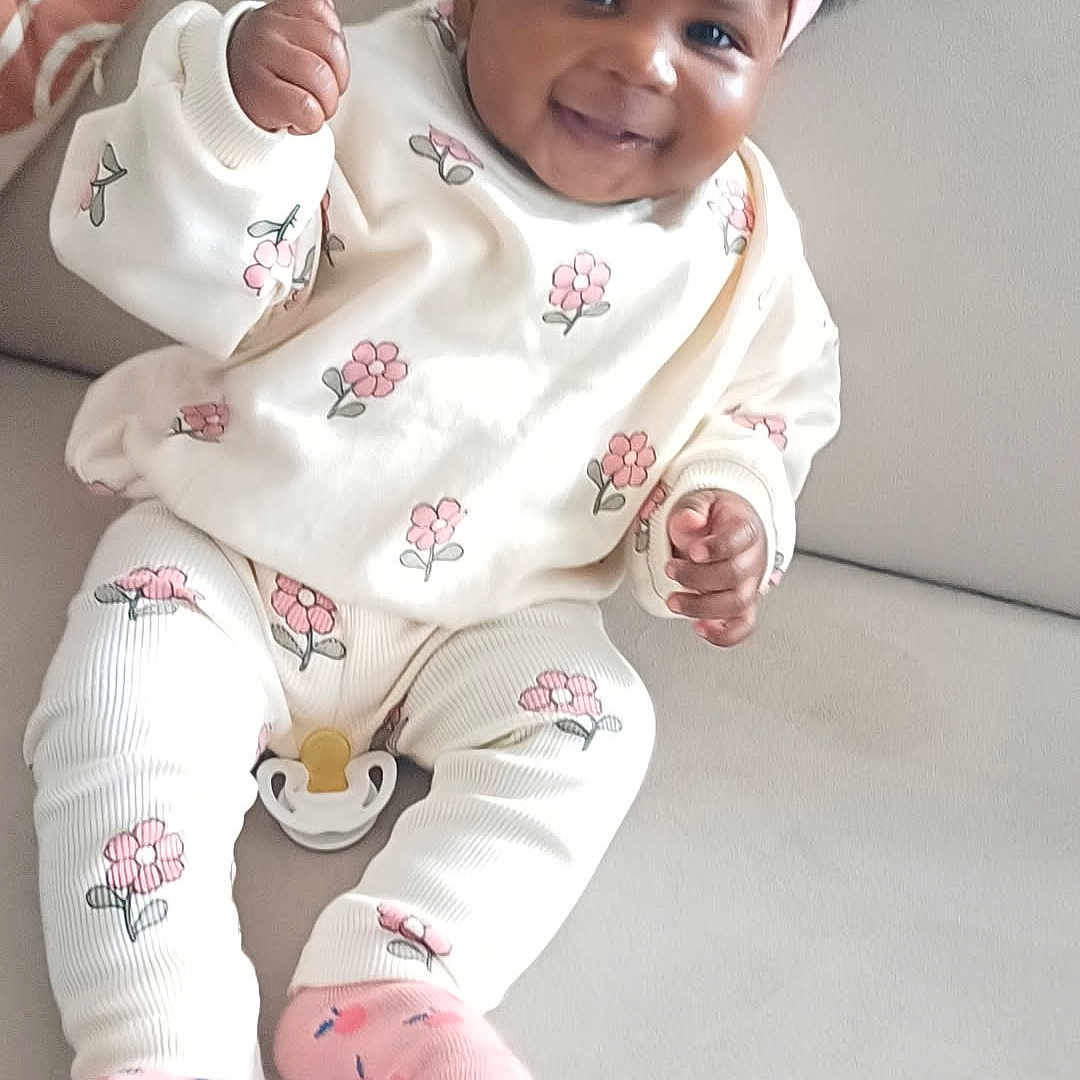 Melissa participe au concours pour gagner de l'argent avec cette photo : baby, child, clothing, couch, cute, fabric, floral, furniture, happy, headband, home, indoor, infant, outfit, person, pink, portrait, seated, smiling, socks