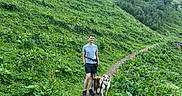 Véo participe au concours pour gagner de l'argent avec cette photo : dog, person, hiker, mountain, mountainscape, trail, hiking, outdoors, nature, wildflowers, greenery, forest, cliffs, valley, landscape, adventure, leash, backpack, summer, scenic