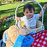 child, toddler, basket, easter_eggs, plush_toy, bunny, grass, picnic_blanket, outdoor, sunlight, smiling, clothing, bow_tie, toy, nature, park, happy, sitting, daylight, cute