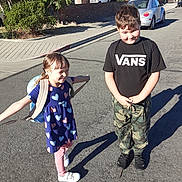 Anastasia is registered to the contest to win money with this photo: child, children, boy, girl, street, backpack, sunlight, smile, playful, casual_clothing, sidewalk, car, residential_area, shadow, tree, curb, daytime, candid, outdoor, happy