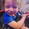 toddler, child, smiling, curly_hair, kitten, animal, indoor, blue_shirt, person, hand, happy, mickey_mouse, toy, seat, candid, cute, baby, pet, holding, closeup