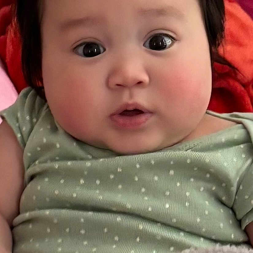 Lilyane Hope joined the competition — help win amazing prizes! adorable, baby, bedding, big_eyes, blanket, chubby_cheeks, close_up, cute, dark_hair, face, fleece_blanket, green_onesie, indoors, infant, lying_down, onesie, polka_dot_pattern, portrait, soft_skin, surprised_expression