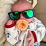 baby, pacifier, sunglasses, onesie, infant, cute, hand, blanket, soft, naptime, reflection, face, clothing, red_trim, blue_anchors, white_fabric, relaxing, indoors, portrait, adorable