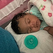 Kateri is registered to the contest to win money with this photo: baby, infant, sleeping, peaceful, portrait, face, curly_hair, blanket, crib, pacifier, pink, turquoise, cozy, indoor, nursery, bed, covered, resting, close_up, child