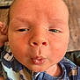 Tucker joined the competition — help win amazing prizes! baby, close_up, face, puckered_lips, infant, blue_outfit, patterned_clothing, skin_texture, indoors, flooring, rug, head, expression, newborn, child, person, cute, portrait, young, skin