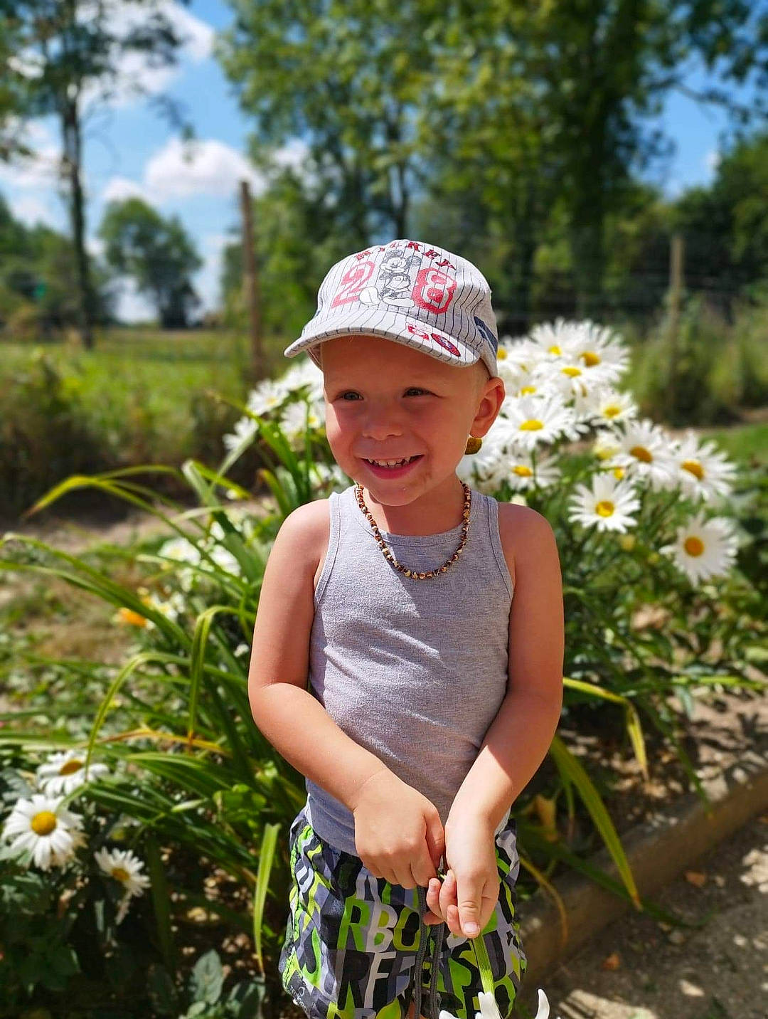 Caïs participe au concours pour gagner de l'argent avec cette photo : baby, baby_toddler_clothing, baseball_cap, cap, flower, grass, grass_family, happy, hat, headwear, joy, leaf, meadow, people_in_nature, person, petal, plant, sky, smile, summer