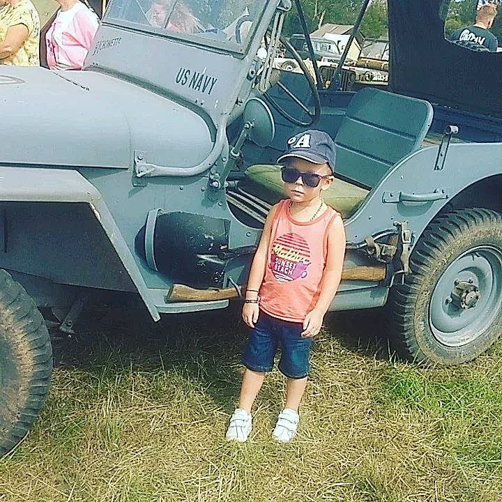 Caïs participe au concours pour gagner de l'argent avec cette photo : auto_part, automotive_design, automotive_exterior, automotive_tire, automotive_wheel_system, blurred, bumper, fender, grass, hat, headwear, hood, motor_vehicle, person, shorts, sneakers, sunglasses, tire, toddler, tread