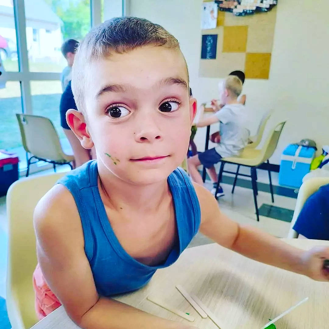 Lyäm participe au concours pour gagner de l'argent avec cette photo : blue, buzz_cut, chair, chest, child, crew_cut, desk, ear, education, eyelash, fun, furniture, happy, learning, leisure, person, picture_frame, room, sitting, t_shirt