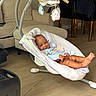 Noah is registered to the contest to win money with this photo: baby, child, infant, smiling, sitting, bouncer, baby_swing, indoor, living_room, furniture, couch, chair, plush_toy, hanging_toy, blanket, blue_clothing, bare_feet, home, portrait, happy