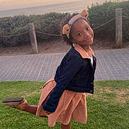Taisha is registered to the contest to win money with this photo: child, girl, smiling, portrait, outdoor, ocean, sea, sunset, sky, grass, park, seaside, coast, dress, jacket, headband, bear_ears, shoes, posing, happy