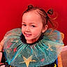 bright, child, colorful, costume, cute, face, fashion, hair, happy, indoor, person, playful, pony_tail, portrait, red_background, sitting, smile, stars, tulle, young