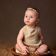 Rosanna is registered to the contest to win money with this photo: baby, child, infant, blue_eyes, headband, pearl, beige_outfit, wooden_bowl, wooden_floor, sitting, curious, portrait, indoor, soft_lighting, background, cute, chubby, button, skin, studio_photo