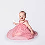 baby, child, pink_dress, headband, smile, sitting, white_background, cute, infant, portrait, happy, young_child, studio_photo, female, one_person, innocence, soft_fabric, tutu, adorable, barefoot