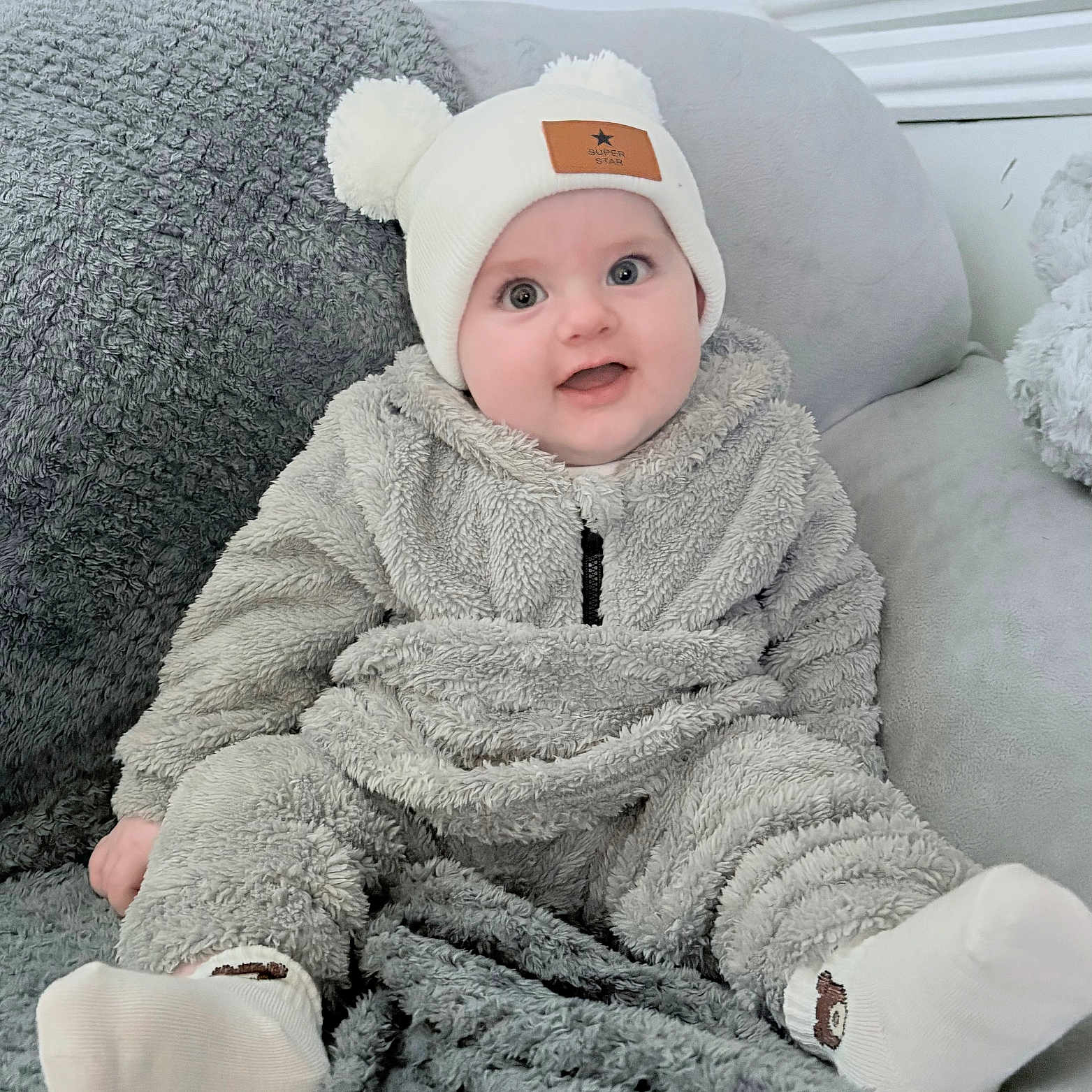 Enzo joined the competition — help win amazing prizes! baby, blanket, child, comfortable, couch, cozy, cute, fluffy_clothing, happy, hat, headwear, indoor, infant, pom_poms, portrait, seated, smiling, socks, soft_texture, warm_clothing